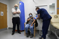 British Prime Minister Boris Johnson, left, watches as a patient receives a COVID-19 vaccine during his visit to the Lordship Lane Primary care center where he met staff and people receiving their booster vaccines, in London, Tuesday, Nov. 30, 2021. (Paul Grover/Pool Photo via AP)