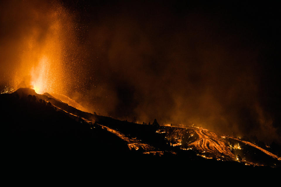 Lava flows from an eruption of a volcano at the island of La Palma in the Canaries, Spain, Sunday, Sept. 19, 2021. A volcano on Spain's Atlantic Ocean island of La Palma erupted Sunday after a weeklong buildup of seismic activity, prompting authorities to evacuate thousands as lava flows destroyed isolated houses and threatened to reach the coast. New eruptions continued into the night. (AP Photo/Jonathan Rodriguez)