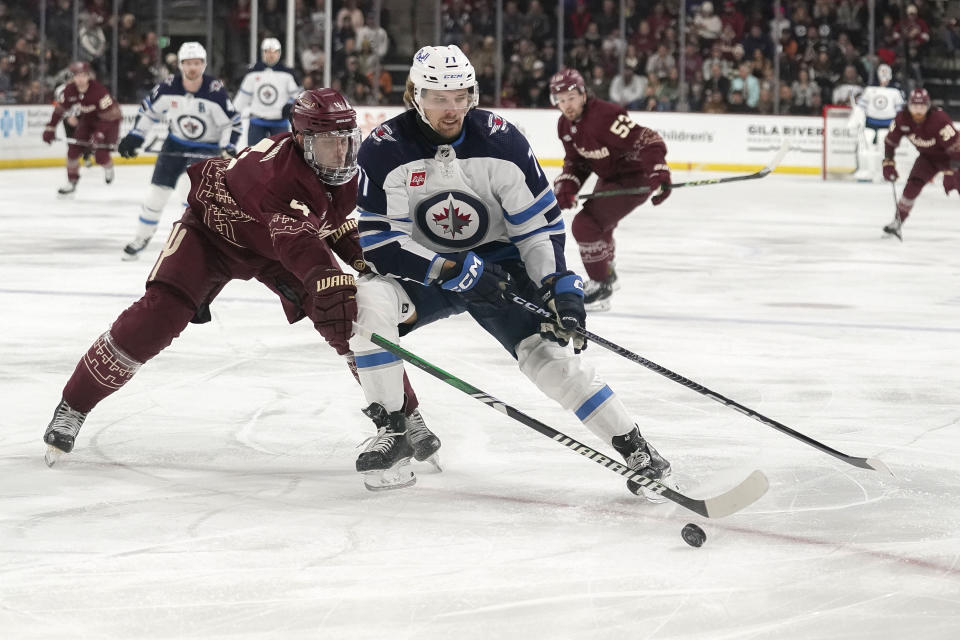 Arizona Coyotes' Juuso Valimaki, left, reaches for the puck in front of Winnipeg Jets' Axel Jonsson-Fjallby, right, during the second period of an NHL hockey game Sunday, Jan. 7, 2024, in Tempe, Ariz. (AP Photo/Darryl Webb)