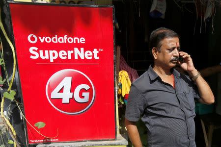 A man speaks on his mobile phone next to a Vodafone advertisement in Kolkata, India, September 26, 2016. REUTERS/Rupak De Chowdhuri