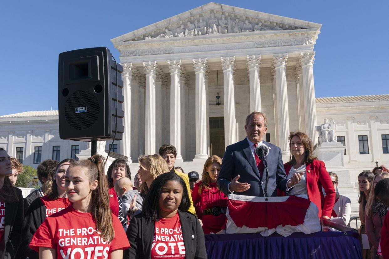 Texas Attorney General Ken Paxton addresses anti-abortion activists at a rally outside the Supreme Court on Nov. 1 on Capitol Hill in Washington, after hearing arguments on abortion in the court, as his wife and state Sen. Angela Paxton, R-McKinney, stands right.