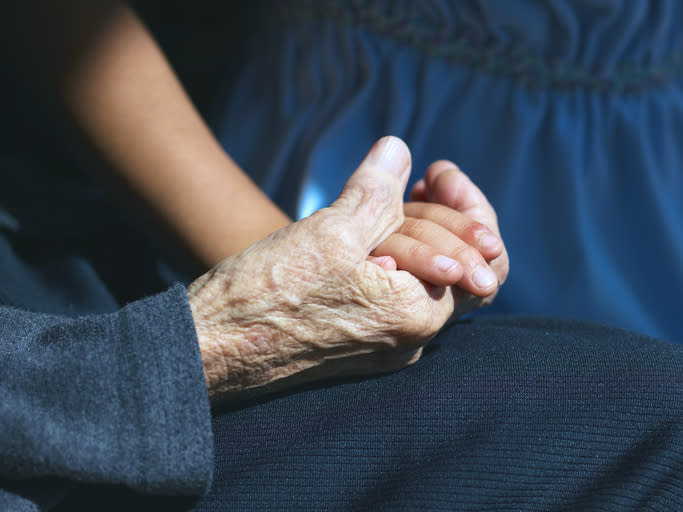 An old woman holds hands with a little girl.