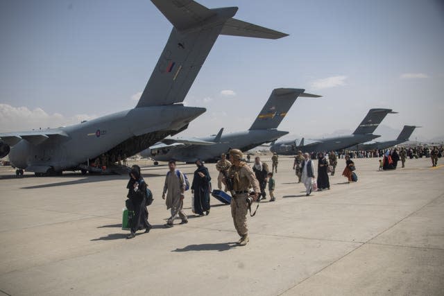 Handout photo issued by the Ministry of Defence (MoD) of members of the UK Armed Forces leading evacuees past ZZ171 (nearest camera), an Royal Air Force Boeing C-17A Globemaster III, at Kabul airport (LPhot Ben Shread/MoD/PA)