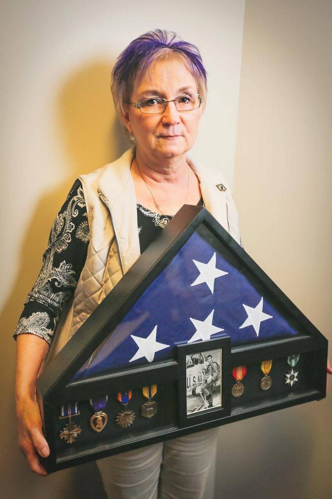 Terri Francisco-Ferrell poses for a photo holding a shadow box with a photo of her brother, San D. Francisco, his medals and U.S. flag. Noelle Haro-Gomez/Tri-City Herald