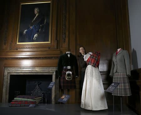 Gallery worker Caroline de Guitaut, curator at the royal collections trust, poses with part of the largest exhibition of The Queen's dresses and accessories ever shown in Scotland at the Palace of Holyroodhouse, Scotland April 20, 2016. REUTERS/Russell Cheyne