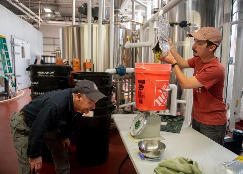 Chuck Tipton keeps an eye on the scale as his son, Benjamin Tipton, pours out the hops while brewing a special Father's Day beer at Bell Tower Brewing Co. in Kent.