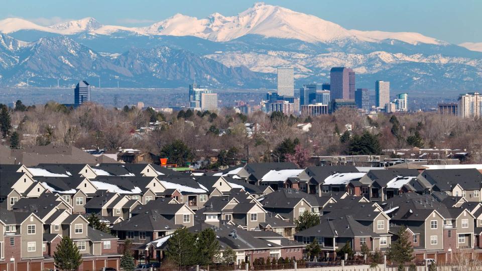 The snow covered Longs Peak and the Rocky Mountains stand behind Downtown Denver skyscrapers, hotels, office and apartment buildings with homes and condos in the foreground.