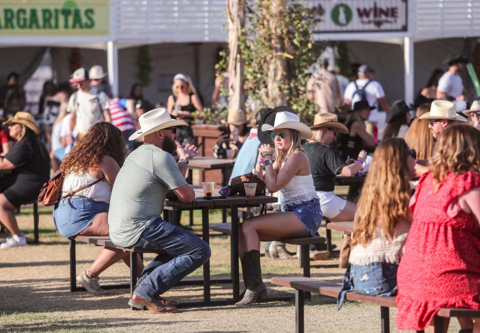 Festivalgoers get drinks and food in one of the concessions areas during the Stagecoach country music festival in Indio, Calif., Friday, April 29, 2022.