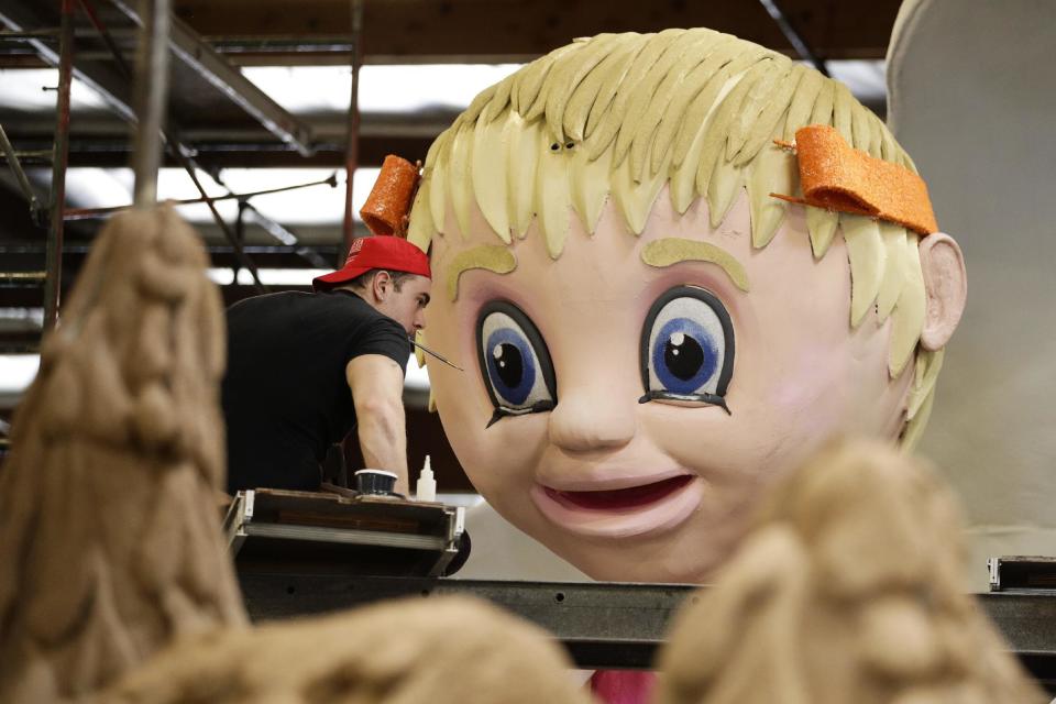 Volunteer Ivo Angelov holds a small brush in his mouth while decorating a float ahead of next week's 128th Rose Parade Wednesday, Dec. 28, 2016, in Irwindale, Calif. (AP Photo/Jae C. Hong)