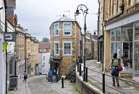 Shoppers are seen walking in one of the older commercial streets in Frome