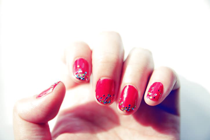 a persons hand with painted fingernails in red with glittery tips