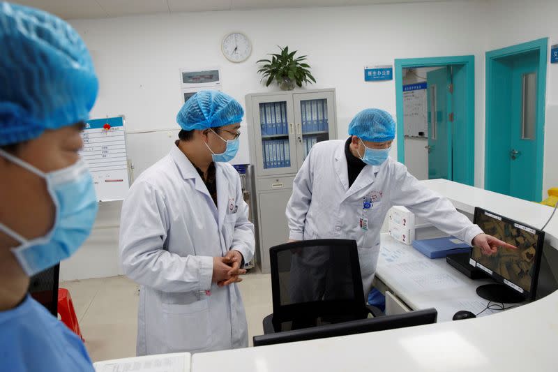 Doctors look at a screen that shows the ward where patients who are infected with the coronavirus are treated at the First People's Hospital in Yueyang