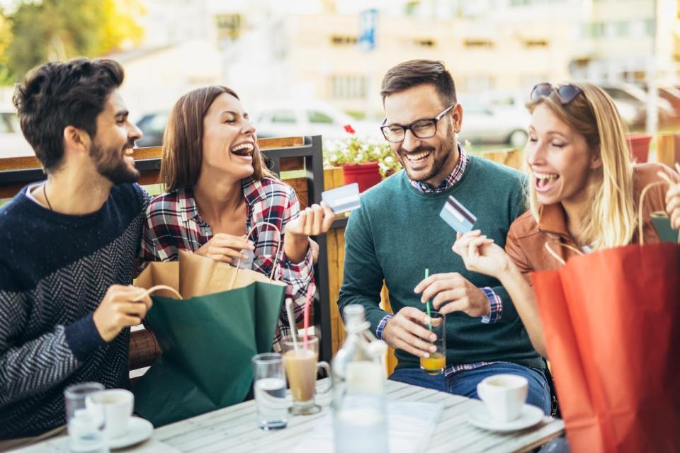 Group of happy friends at a cafe holding their credit cards