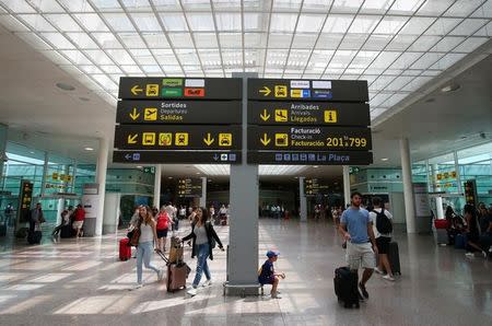 People walk under a sign at Barcelona-El Prat airport, Spain August 4, 2017. REUTERS/Albert Gea