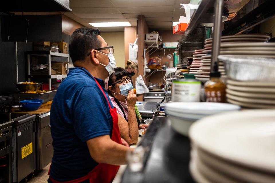 Cam Valle, left, and Barbara Valle, right, co-owners of Cafe Fiesta in Woodbury, prepare meals for customers in the kitchen.