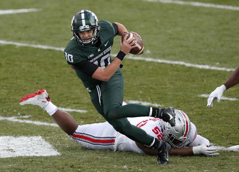 Michigan State quarterback Payton Thorne (10) scrambles against Ohio State's Kyle King (52) during the second half of an NCAA college football game, Saturday, Dec. 5, 2020, in East Lansing, Mich. Ohio State won 52-12. (AP Photo/Al Goldis)