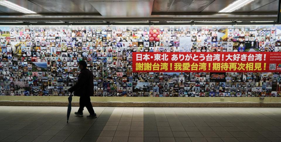 一位民眾經過展示日本東北民眾感謝台灣的照片牆。   圖：張良一/攝