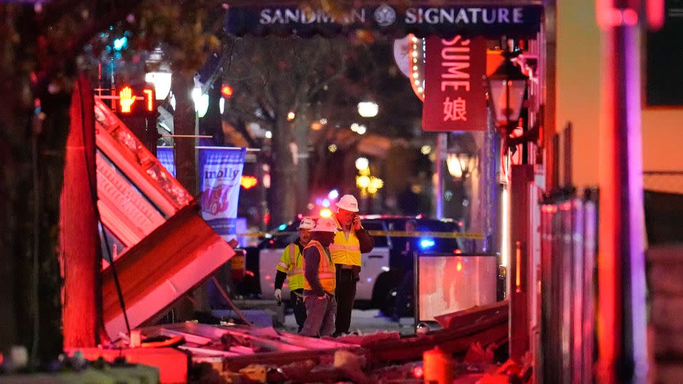 Workers survey damage near the Sandman Signature hotel following an explosion on Monday. - Julio Cortez/AP