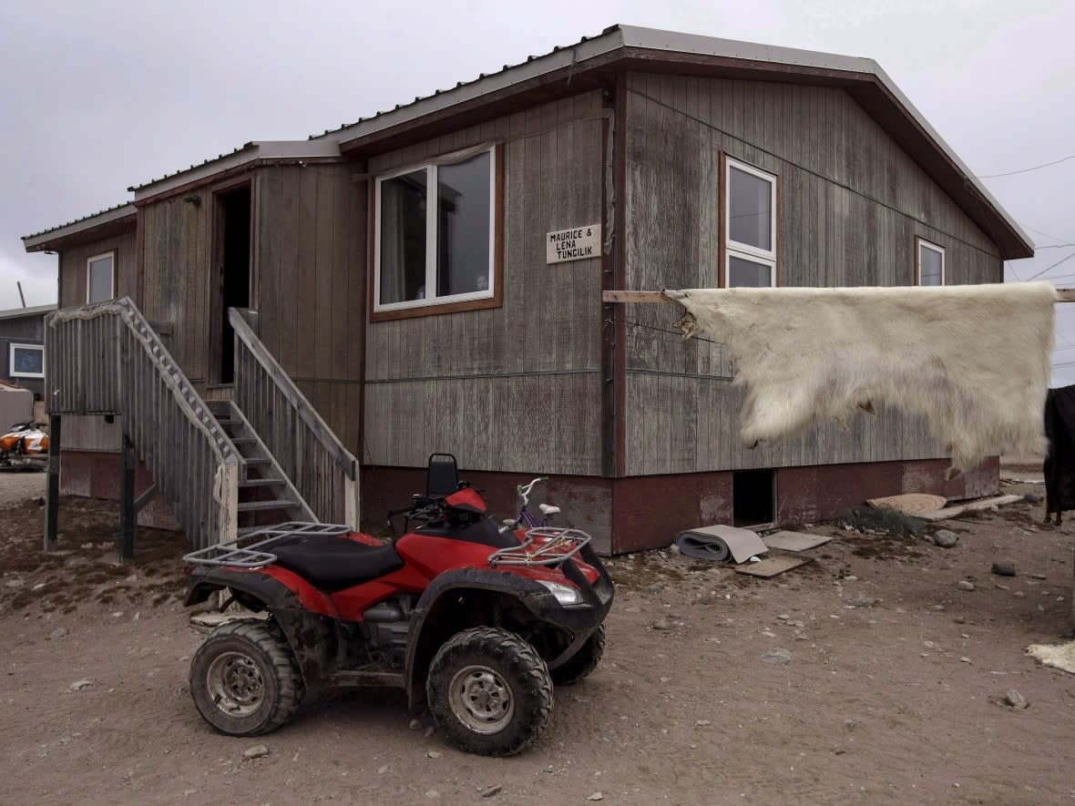 A polar bear hide hangs drying outside of a house in the town of Gjoa Haven, Nunavut in September of 2017. Lorne Kusugak, the territory's minister of housing, said the government will not award contracts for housing in Gjoa Haven, Taloyoak or Kugluktuk after bids came in too high.  (Jason Franson/Canadian Press - image credit)