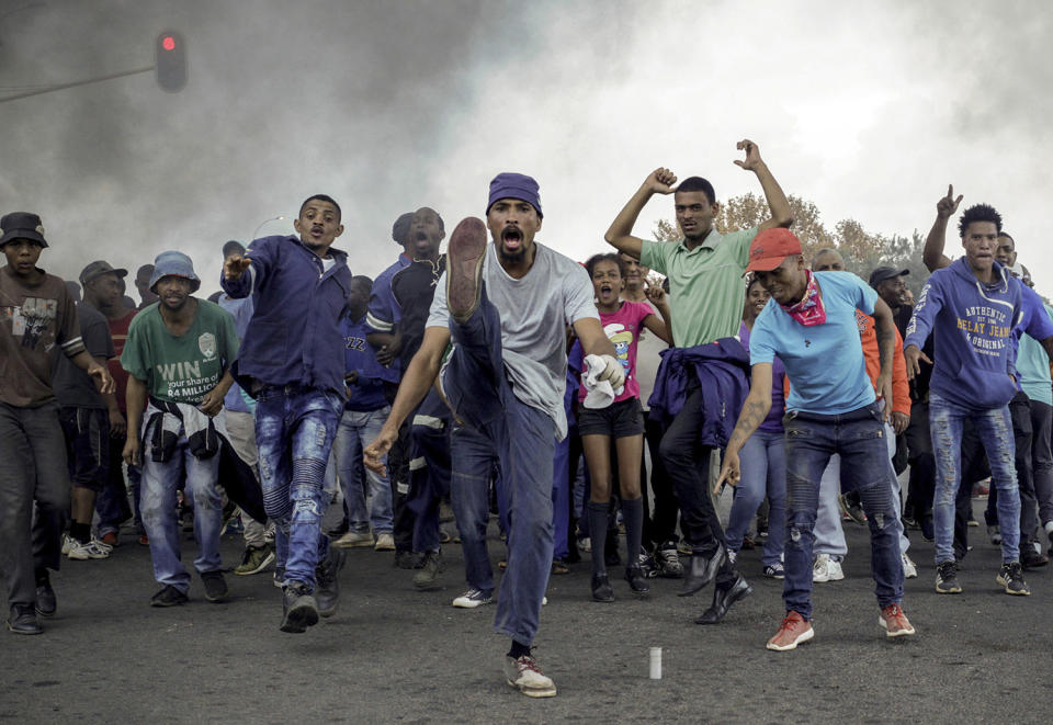 Protesters sing and chant in front of a burning barricade in Johannesburg