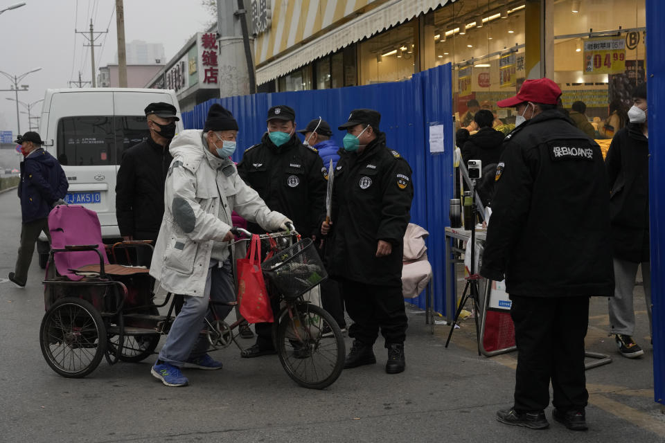 Security guards control access into a community under lockdown in Beijing, Thursday, Nov. 24, 2022. China is expanding lockdowns, including in a cental city where factory workers clashed this week with police, as its number of COVID-19 cases hit a daily record. (AP Photo/Ng Han Guan)