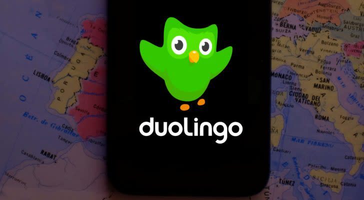 The Duolingo (DUOL) logo on a smartphone screen with a map in the background.
