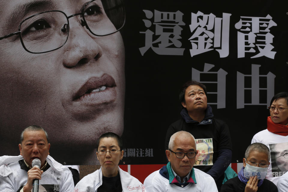 Pro-democracy protesters shave their heads in front of the banner featuring a portrait of Liu Xia, the detained wife of Chinese Nobel Peace laureate Liu Xiaobo during a demonstration in Hong Kong Friday, Feb. 14, 2014 as they demanded Chinese government to release Liu Xia from house arrest. The banner reads "Free Liu Xia." (AP Photo/Kin Cheung)