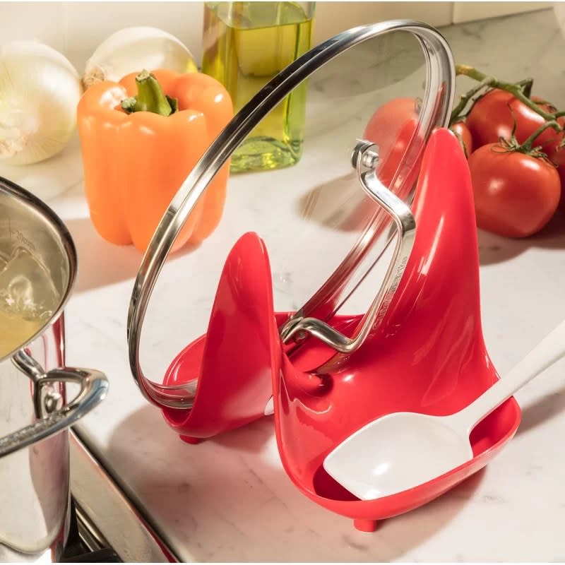 The lid and spoon rest holding a lid and spoon on a kitchen counter