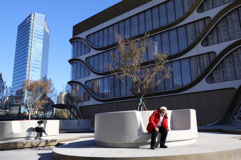 Man rests in front of a shopping mall at the the Kaisa Plaza developed by Kaisa Group Holdings, in Beijing