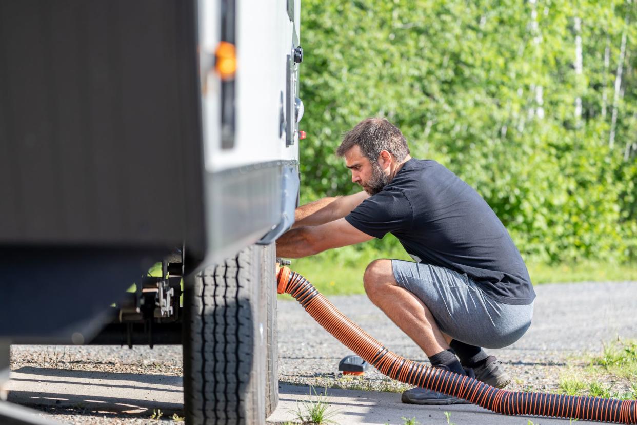 Man Emptying RV Sewer at Dump Station After Camping