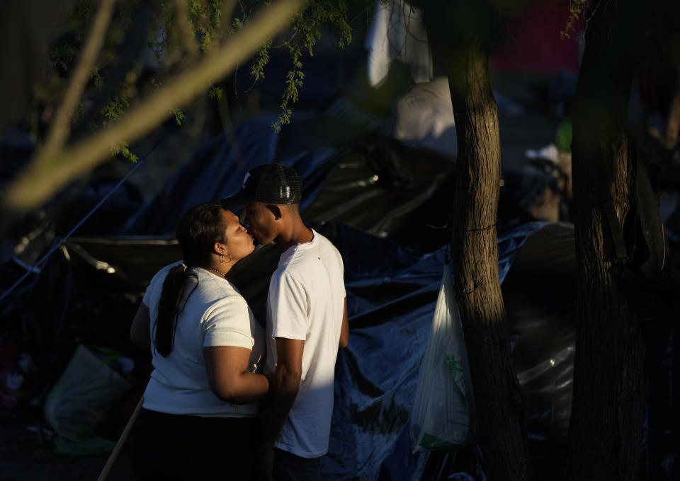 A Venezuelan migrant couple kiss outside their tent at a makeshift camp of migrants on a river bank in Matamoros, Mexico, Thursday, Dec. 22, 2022. (AP Photo/Fernando Llano)