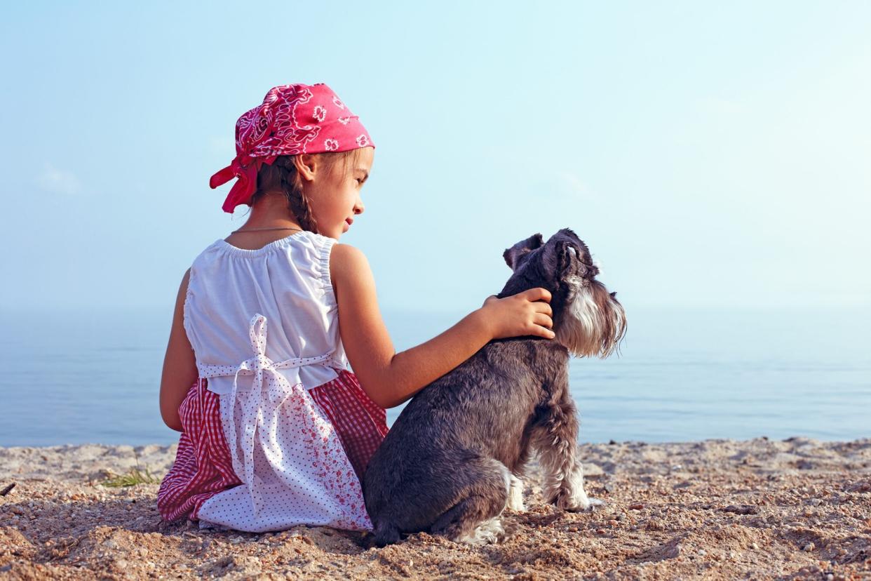 Girl sits with terrier on beach