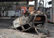 A burnt car lies overturned at a damaged fuel station after it was set on fire by a mob in a riot affected area after clashes erupted between people demonstrating for and against a new citizenship law in New Delhi