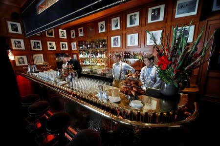 Employees stand behind the “Bar de l'Escadrille” (the squadron bar) at the Fouquet's restaurant on the eve of its reopening on the Champs Elysees, almost 4 months after it was ranksacked by a "yellow vests" protest in Paris