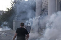 A man hurls a tear gas canister at riot police on the steps of the Serbian parliament during a protest in Belgrade, Serbia, Wednesday, July 8, 2020. Police have fired tear gas at protesters in Serbia's capital during the second day of demonstrations against the president's handling of the country's coronavirus outbreak. President Aleksandar Vucic backtracked on his plans to reinstate a coronavirus lockdown in Belgrade this week, but it didn't stop people from firing flares and throwing stones while trying to storm the downtown parliament building. (AP Photo/Marko Drobnjakovic)