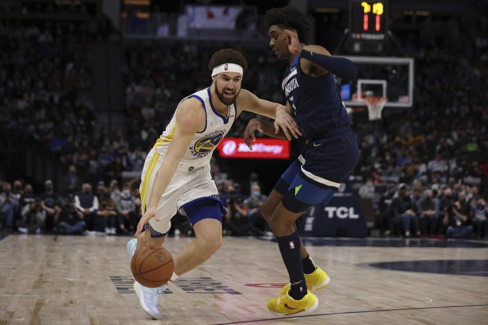 Golden State Warriors guard Klay Thompson (11) handles the ball against Minnesota Timberwolves forward Jaden McDaniels (3) during the second half of an NBA basketball game, Sunday, Jan. 16, 2022, in Minneapolis. (AP Photo/Stacy Bengs)