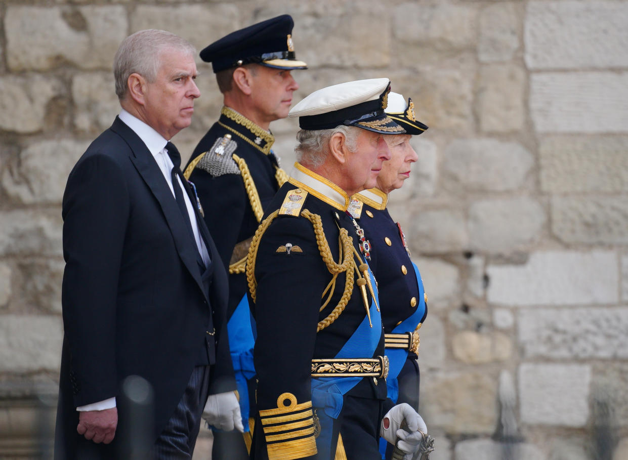 The Duke of York, the Earl of Wessex, King Charles III and the princess royal walk in front of a stone wall.