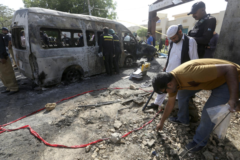 Pakistani investigators gather evidence at the site of explosion, in Karachi, Pakistan, Tuesday, April 26, 2022. The explosion ripped through a van inside a university campus in southern Pakistan on Tuesday, killing several people including Chinese nationals and their Pakistani driver, officials said. (AP Photo/Fareed Khan)