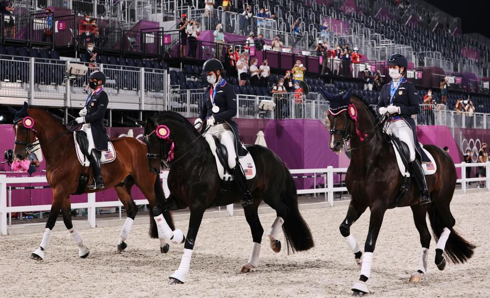 Silver medalists Adrienne Lyle, Steffen Peters and Sabine Schut-Kery of the United States ride together after the medal ceremony of the Equestrian Dressage team final.