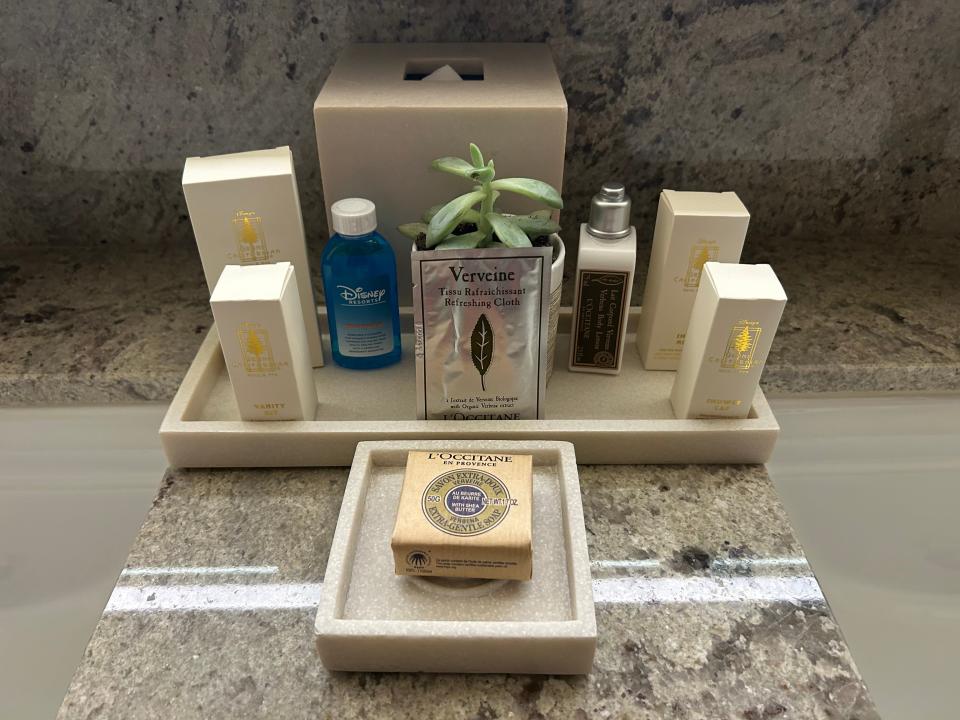 A bathroom counter with a variety of toiletries, including mouthwash, soap, and lotion. There is also a box of tissues.