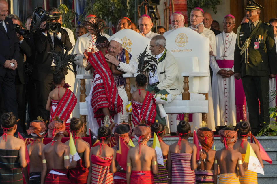 Pope Francis hugs a child in traditional dress as he attends with East Timor's President José Manuel Ramos-Horta, seated at right, a welcome ceremony outside the Presidential Palace in Dili, East Timor, Monday, Sept. 9, 2024. Pope Francis arrived in East Timor on Monday to encourage its recovery from a bloody and traumatic past and celebrate its development after two decades of independence from Indonesian rule. (AP Photo/Gregorio Borgia)