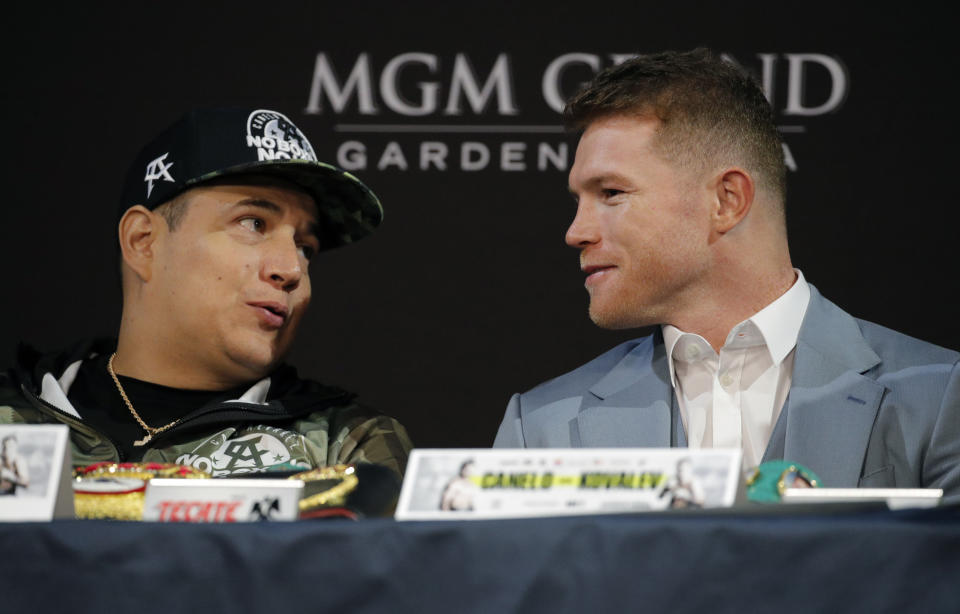 Canelo Alvarez, right, speaks with trainer Eddy Reynoso during a news conference Wednesday, Oct. 30, 2019, in Las Vegas. Alvarez is scheduled to fight Sergey Kovalev in a WBO light heavyweight title bout Saturday in Las Vegas. (AP Photo/John Locher)