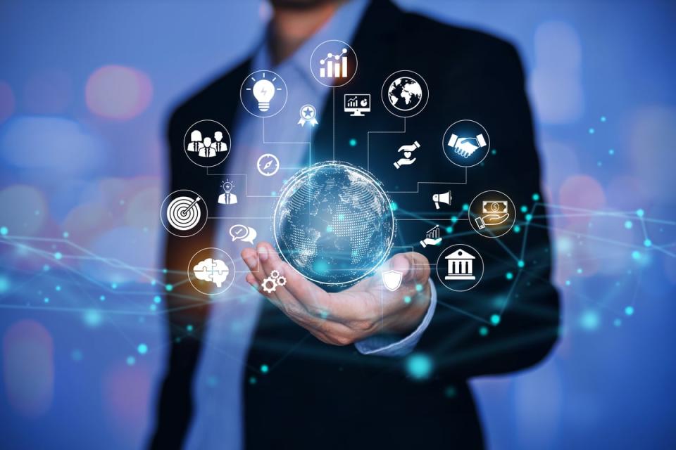 A view of a person in professional attire holding a globe with various icons surrounding it.