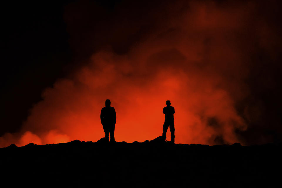 Dos personas observan la erupción del un volcán, al norte de Grindavík, Islandia, el 8 de febrero de 2024. (AP Foto/Marco Di Marco)