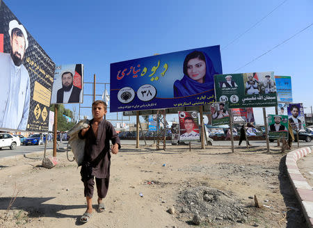 Election posters of parliamentary candidates are installed on a street while a boy walks past in Jalalabad, Afghanistan October 6, 2018. REUTERS/Parwiz