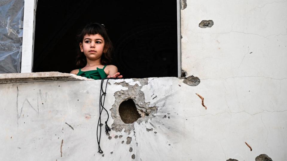 PHOTO: A Palestinian girl looks out of the window of a shrapnel-pocked building in Jenin on May 23, 2024 in the aftermath of a raid by Israeli forces in the occupied West Bank city on May 21, 2024. (Ronaldo Schemidt/AFP via Getty Images)