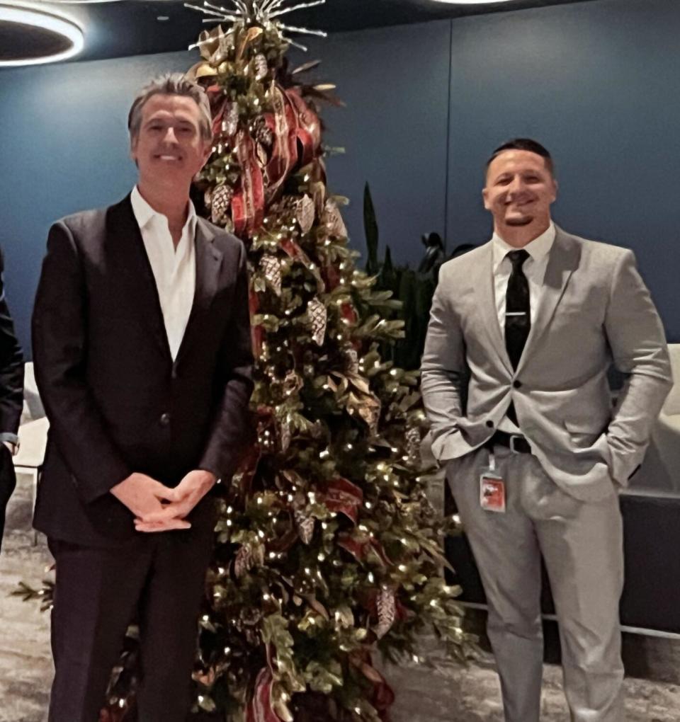 Two men in suits flank a Christmas tree.