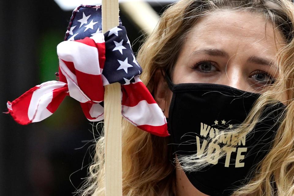 Lindsey Schwartz wears a mask with a message as she holds a sign during the Women's March in downtown Chicago, Saturday, Oct. 17, 2020.