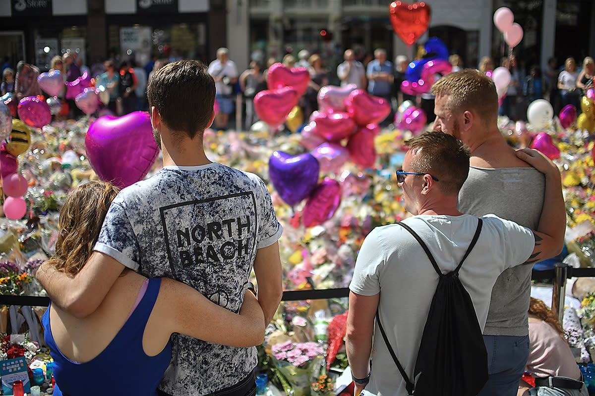 Couples comfort one another as flowers and balloons are left in Saint Ann's Square in tribute to those killed in an explosion at the Manchester Arena earlier this week: Getty Images