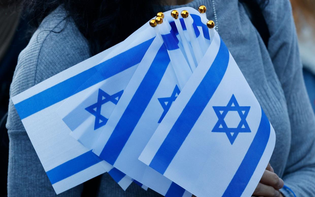 A supporter holds multiple Israeli flags